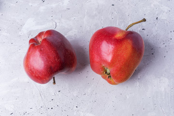 Close-up two ugly red apples on grey concrete background. 
