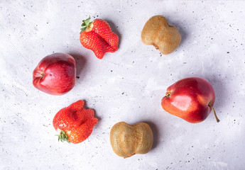 Six ugly fruits and berries laid out in circle on grey concrete background. 