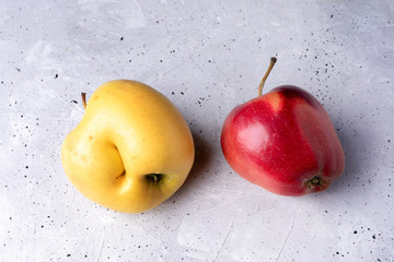 Two ugly red and yellow apples on grey concrete background.