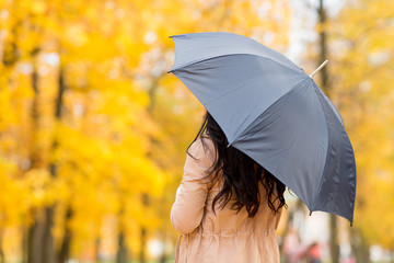 season, rainy weather and people concept - young woman with umbrella in autumn park