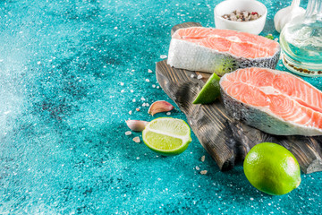 Raw salmon fish steaks with spices, on marine blue concrete stone background copy space