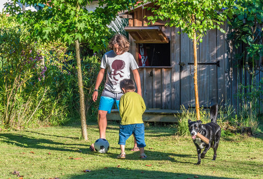 Two boys of five years old and thirteen years old playing with a ball in the garden