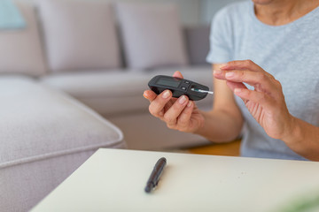 Close up of woman hands checking blood sugar level by Glucose meter using as Medicine, diabetes, glycemia, health care and people concept. Medicine, age, diabetes, health care and people concept