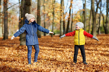 Naklejka na ściany i meble childhood, season and people concept - happy children having fun at autumn park