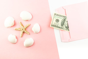 Money in a pink envelope, starfish, seashells on a blue background. Travel budget. Copy space, top view. 