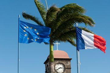 Church bell tower under palm tree and flags, St Joseph, La Reunion, Oversea territories, France