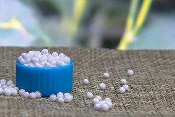 Close image of Homeopathic granules in small bottle cap and some granules scattered on the jute...