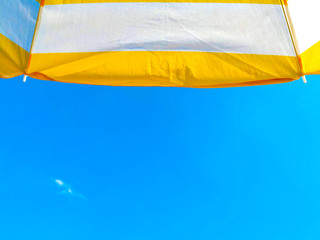 Yellow beach umbrella and blue sky   on a sunny day 