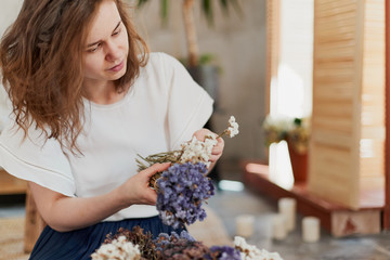 Young focused female collecting dried statice flowers