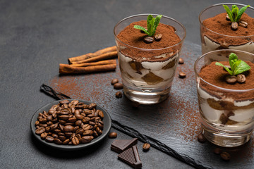 Classic tiramisu dessert in a glass on stone serving board on dark concrete background