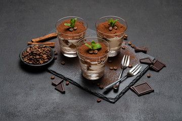 Classic tiramisu dessert in a glass on stone serving board on dark concrete background