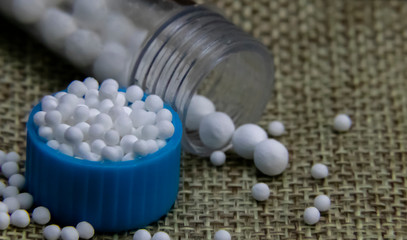 Close-up of Homeopathic granules in small bottle cap and medicine bottles with some granules...