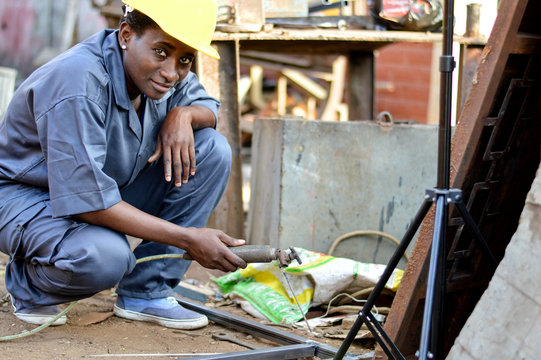 Young woman soldering to make an iron door.
