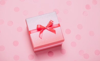 Pink present box on pink konfetti background.