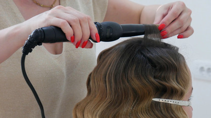 Professional hairdresser hands curling hair in the salon. 