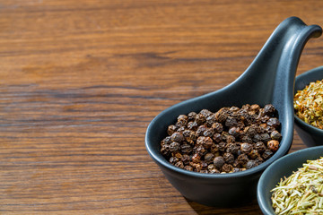 different spices and herbs in spoons or bowls on a brown wooden background . Food and cuisine ingredients  .Dried rosemary,black pepper,red paprika powder or Cayenne Pepper ,oregano close up