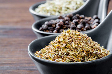 different spices and herbs in spoons or bowls on a brown wooden background . Food and cuisine ingredients  .Dried rosemary,black pepper,red paprika powder or Cayenne Pepper ,oregano close up