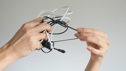 Black and white cables in a woman's hand on isolated background