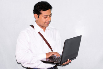 Portrait of Indian businessman man using laptop or computer in studio on white/gray background.