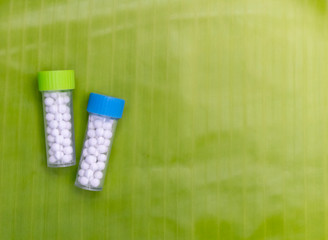 Natural Homeopathy Concept - A homeopathy concept with homeopathic pills bottles on banana leaf background