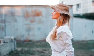 profile of a girl in a white dress at sunset model in a hat