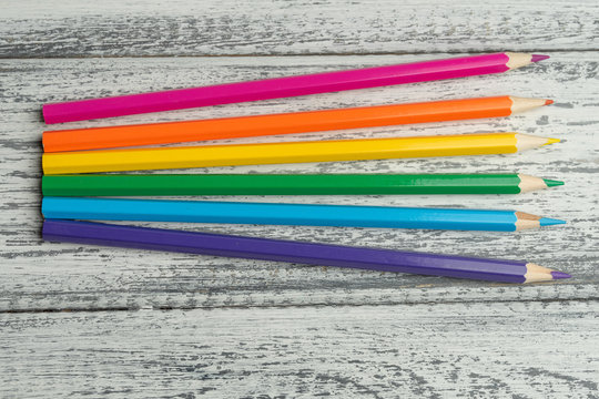 Pride flag, LGBT. Colored pencils forming a rainbow on white wooden background. Red, orange, yellow, green, blue, purple. Stationery