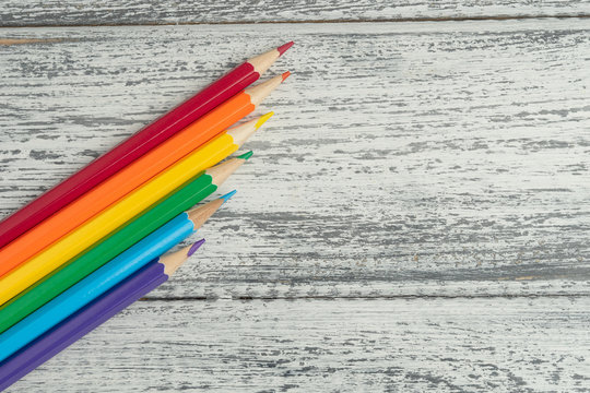 Concept of LGBT. Colored pencils lies as a Pride flag flag. Located on a on white wooden background. Top view. Copy space