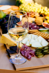Photo of a fantastic, beautifull snacks such as fruits, cheese, olives, dried meat  for wine on a wooden table with wine glass