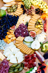 Photo of a fantastic, beautifull snacks such as fruits, cheese, olives, dried meat  for wine on a wooden table 