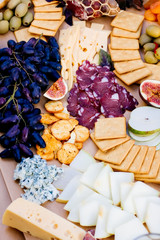 Photo of a fantastic, beautifull snacks such as fruits, cheese, olives, dried meat  for wine on a wooden table 