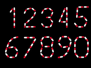 numbers 1, 2, 3, 4, 5, 6, 7, 8, 9, 0 written in red and white medical capsules, isolated on a black background