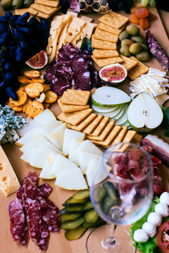 Photo of a fantastic, beautifull snacks such as fruits, cheese, olives, dried meat  for wine on a wooden table with wine glass