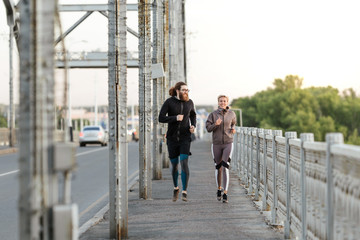 Long-haired guy with a girl on a joint morning jog around the city through the car bridge