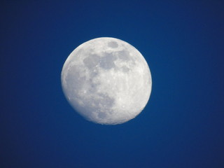 Genova, Italy - 06/15/2019: An amazing photography of the full moon over the city of Genova by night with a great clear and blue sky in the background and some stars.
