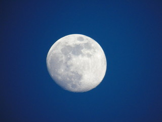 Genova, Italy - 06/15/2019: An amazing photography of the full moon over the city of Genova by night with a great clear and blue sky in the background and some stars.