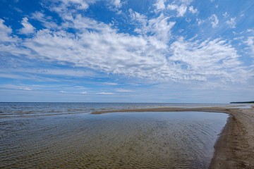 dramatic colorful clouds over sandy beach at the sea with blue sky