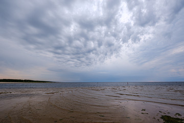 dramatic colorful clouds over sandy beach at the sea with blue sky