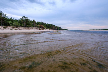 dramatic colorful clouds over sandy beach at the sea with blue sky