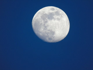 Genova, Italy - 06/15/2019: An amazing photography of the full moon over the city of Genova by night with a great clear and blue sky in the background and some stars.