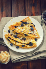 Homemade crepes with blueberries, coconut flakes and chocolate sauce