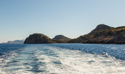 Naklejka premium Track trail behind of speed boat on sea surface with clear sky in background.