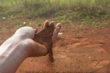 Hand man holding red soil dust on the blur background 