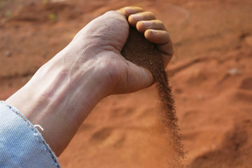 Hand man holding red soil dust on the blur background 
