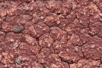 Rock is red. Small stones, cracks.