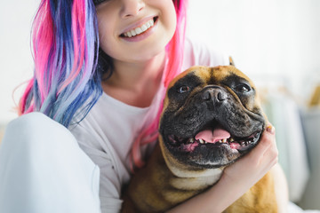 cropped view of happy girl with colorful hair hugging cute bulldog