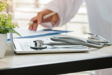 Doctor working in hospital writing prescription clipboard, working an Laptop on desk in hospital with report analysis, Healthcare costs and fees in medical hostpital office