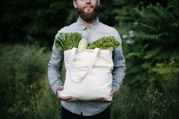Man holding an eco bag filled with grocery. Vegetables and fruits. Ecology concept environment...