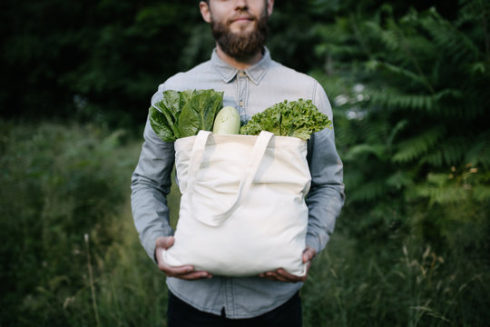 Man holding an eco bag filled with grocery. Vegetables and fruits. Ecology concept environment protection.