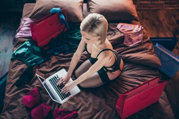 Top above high angle view of her she nice-looking gorgeous attractive lovely feminine lady sitting on bed order new diverse clothes collection in loft brick wooden industrial style interior © deagreez