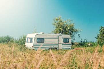 White trailer trailer house on wheels in the grass. Affordable Housing